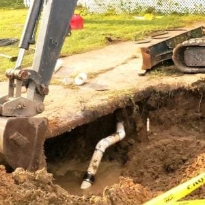Image of an excavator covering a 4" sewer line repair next to a driveway in a Pensacola, Florida home.