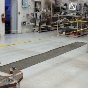 Image of a secured job site with caution tape and drying concrete poured by Honey Bee Plumbing after performing a commercial drain repair in a Pensacola, Florida business.