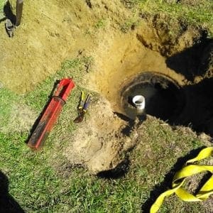 Image of an excavated septic tank access cover to clean field drain filter on a Pace, Florida home on Easter Sunday.