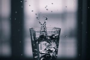 Clear glass of clean water with droplets splashing out