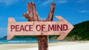 Wooden "Peace of Mind" arrow sign on a beach