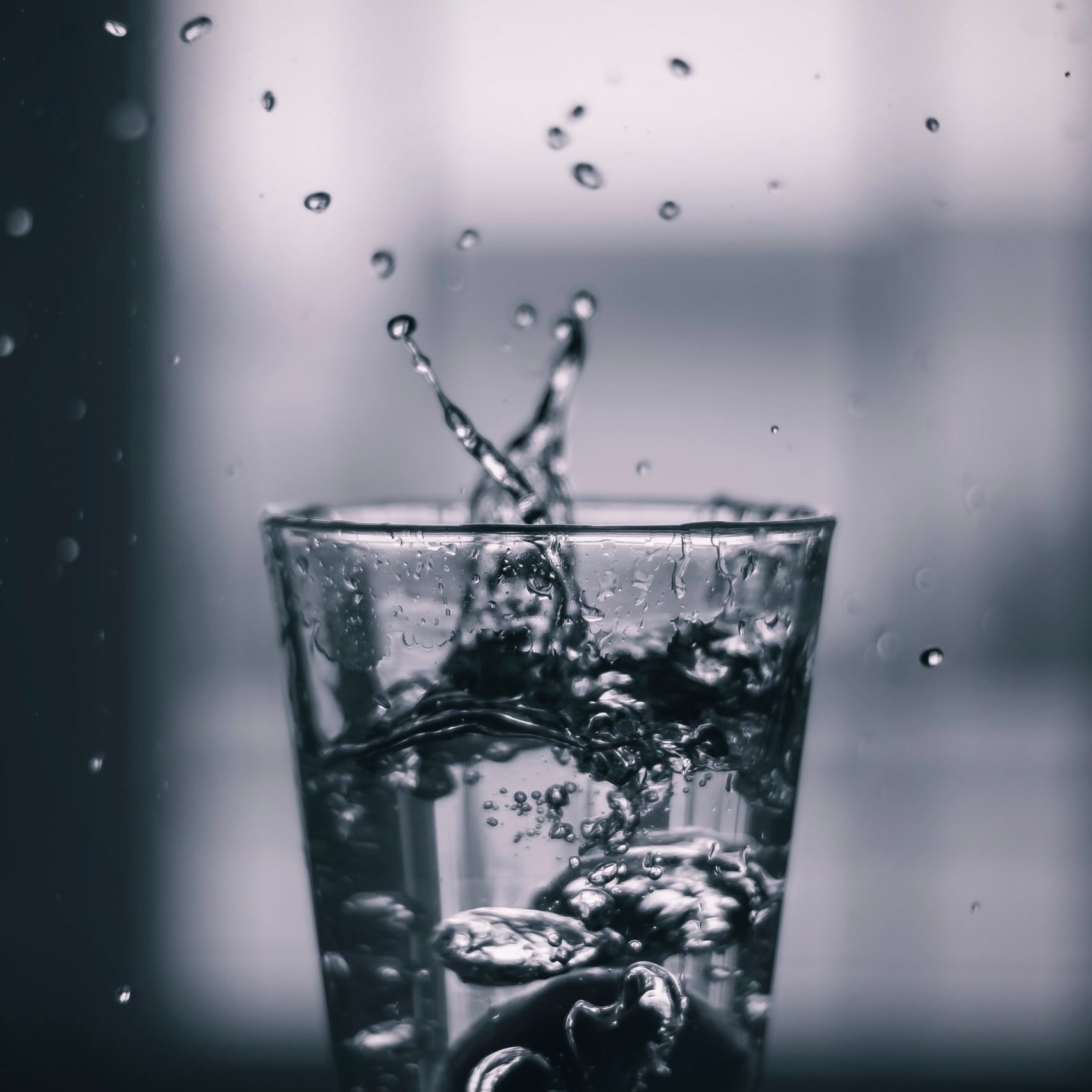 The Essence of Purity: Clean Water Splashing from a Glass Clear glass of clean water with droplets splashing out