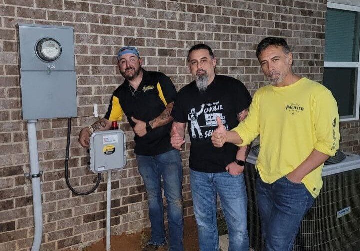 Expert plumber Jason Bailey with satisfied clients near a lift station control panel