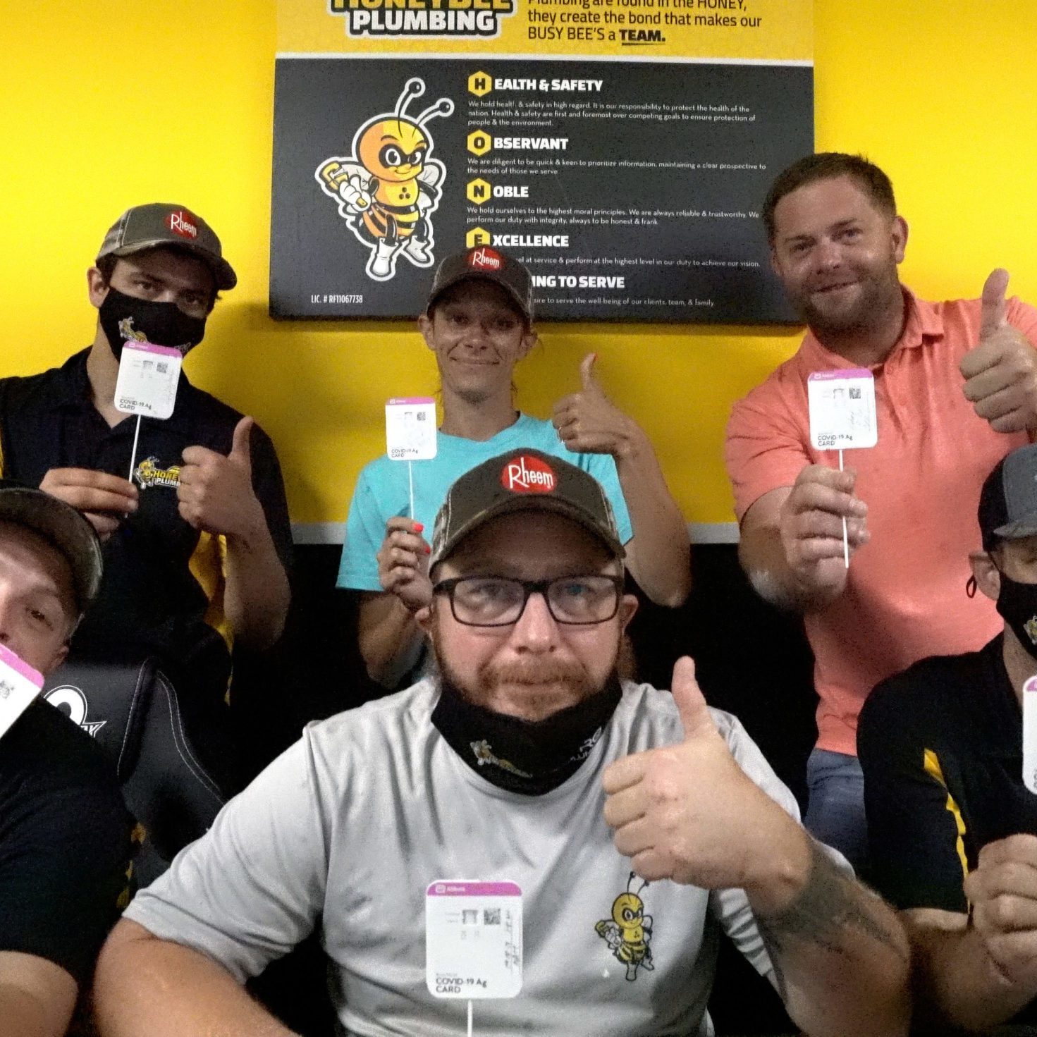 A Safe and United Team: Honey Bee Plumbing Celebrates Negative COVID-19 Results Honey Bee Plumbing team standing in front of a core values poster, celebrating their negative COVID-19 test results