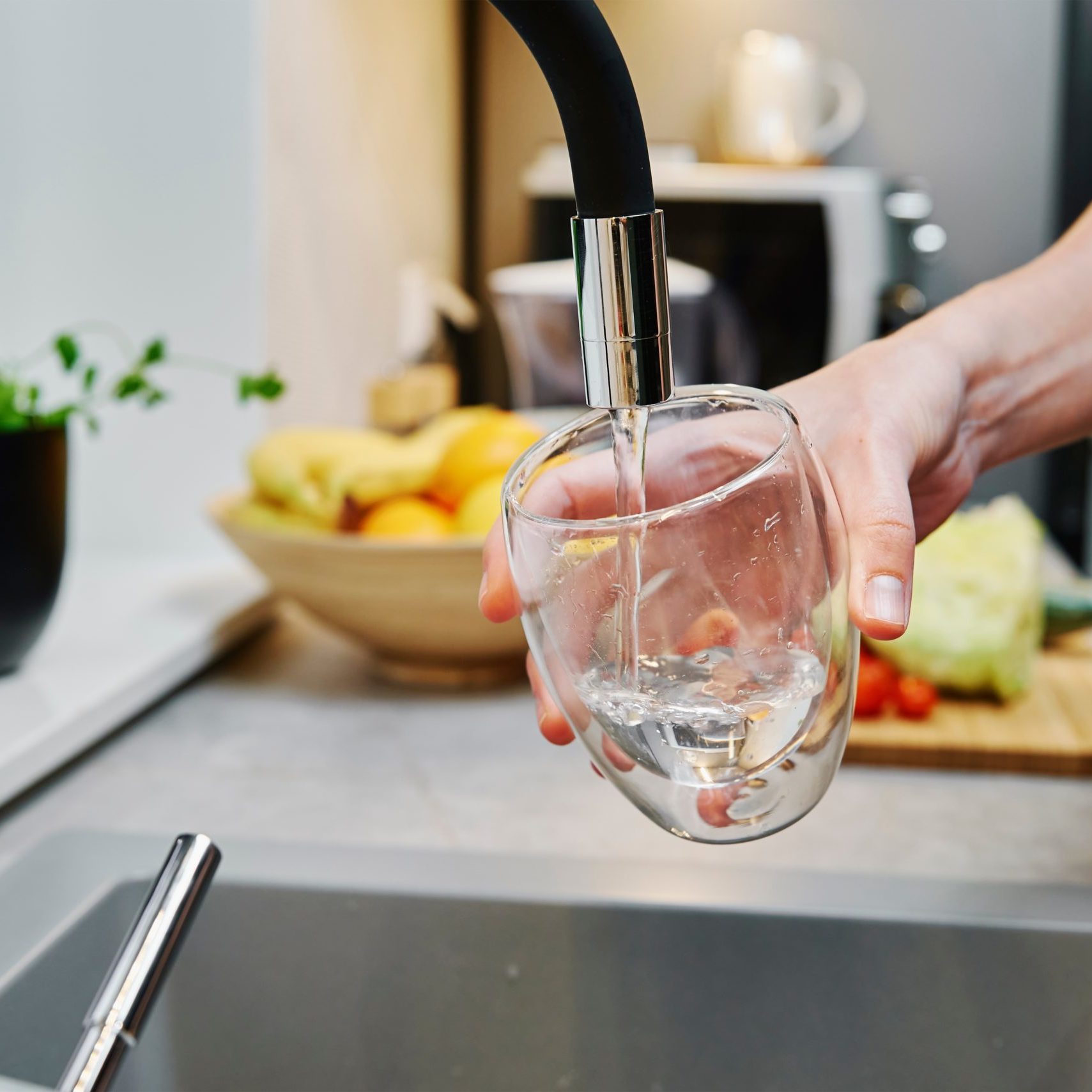 Woman pouring water into a glass from a kitchen faucet